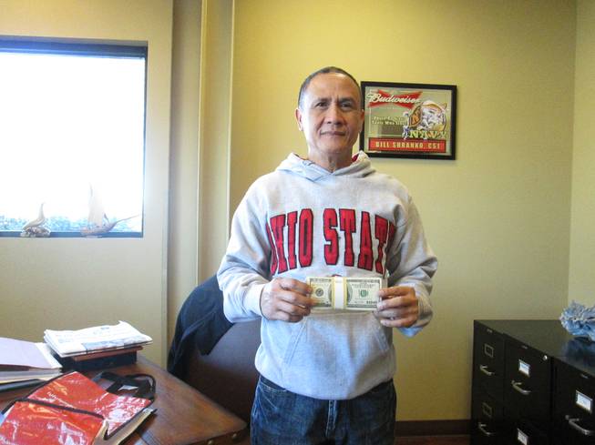 Cab driver Gerardo Gamboa poses with the $10,000 he received from an unidentified gambler who rewarded him for turning over $300,000 the gambler had left behind in Gamboa's taxi.
